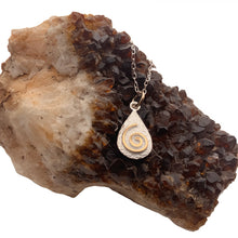 Lade das Bild in den Galerie-Viewer, Keltische Kette aus Silber mit einer vergoldeten Spirale auf weißem Hintergrund. Original Irischer Schmuck, platziert auf auf eine braunen Kristall.